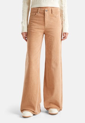 Pantaloni a gamba larga in corduroy di un morbido colore beige, con vita alta, tasche frontali e una sottile texture del tessuto.