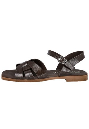Sandalia plana marrón oscuro con tiras cruzadas brillantes, hebilla ajustable en el tobillo y suela marrón clara.