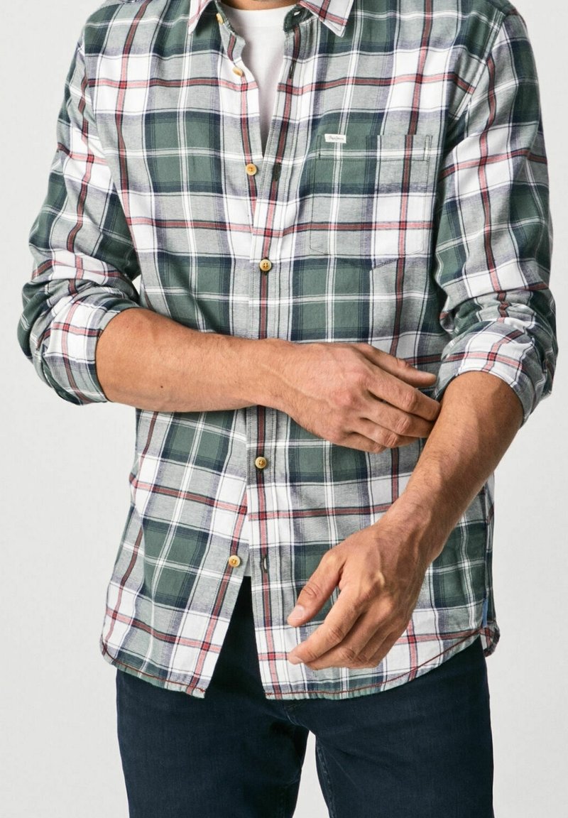 Randig knapp-up skjorta i grönt, vitt och rött, med en ficka på vänster bröst och uppvikt ärmar. Gjord av lättviktigt tyg.