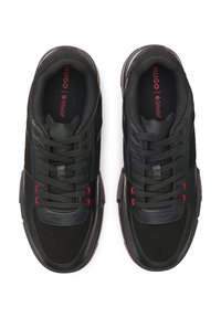 Sneakers nere con una combinazione di texture opache e lucide. Presentano accenti e lacci rossi, collo imbottito e dettagli traforati.