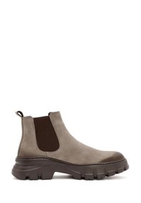 Bottines Chelsea en daim marron avec des panneaux élastiques sur les côtés, semelle en caoutchouc épaisse et tirette. Présente une finition lisse et des accents texturés.