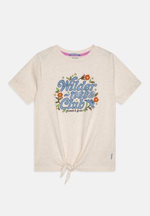 T-shirt en coton beige à manches courtes, avec un design graphique bleu portant l'inscription "Wilderness Club" et des accents floraux. Détail en nœud à l'ourlet.
