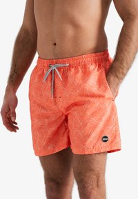 Koraal kleurige zwembroek met een bladenpatroon, elastische tailleband, trekkoord en zijzakken. Bevat een klein logo-opdruk op de zoom.