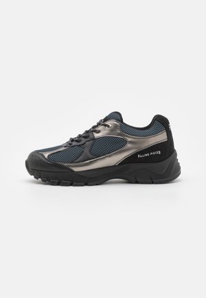Sort og metalgrå sneaker med mesh-paneler, tyk sål, snørelukning og "Filling Pieces" branding på siden og hælen.