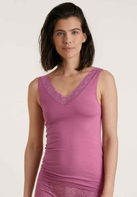 Roze tanktop met een V-hals versierd met delicate kantafwerking aan de randen. Gemaakt van een zachte, rekbare stof die soepel om het lichaam valt.