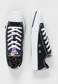 Svarta canvas sneakers med vita gummisulor, snördesign, kontrasterande sömmar och leopardmönstrad foder. Har blå och röda accentfärger.