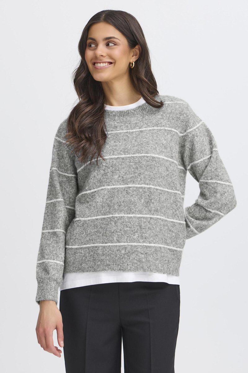 Pull rayé gris avec des lignes blanches, col rond, texture tricotée, manches longues. Porté par-dessus une chemise blanche, associé à un pantalon sombre.