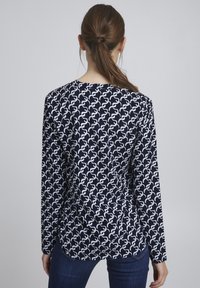 Navy long-sleeve shirt featuring a white abstract pattern. Soft fabric with a round neckline and curved hem. Slim fit design.