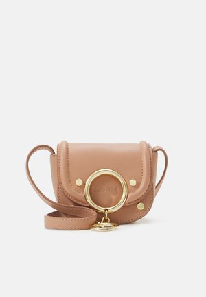 Sac bandoulière en cuir beige avec un accent métallique circulaire doré, fermeture à rabat et petits clous ; comprend une sangle amovible.