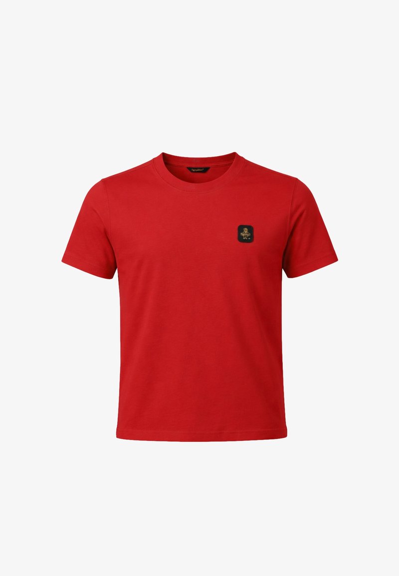 Maglietta rossa a maniche corte con scollo rotondo e una piccola toppa quadrata nera sul petto a sinistra.