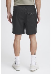 Mustad lühikesed püksid elastsest vöökohast, ühe tagatasku ja nööbiga, sirge lõikega. Kandmisega valged sokid ja kingad.