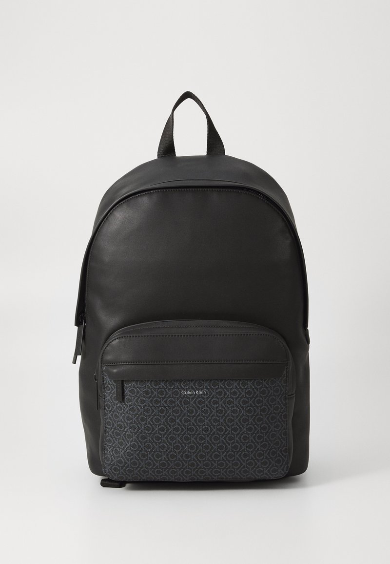 Zaino nero con superficie in similpelle liscia e tasca frontale in tessuto con motivo che presenta il logo Calvin Klein. Due spallacci e maniglia superiore.