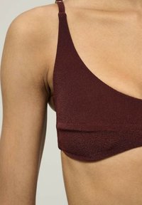 Burgundi színű bralette, textúrált kötött dizájnnal, vékony pántokkal és sima felülettel, amely a minimális stílust és formát emeli ki.