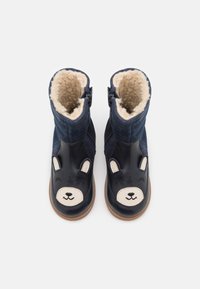 Granatowe botki z futrzanym wykończeniem i wzorem twarzy misia. Skórzany przód z uszkami, przeszyciami oraz bocznym zamkiem zapewniającym łatwe zakładanie.