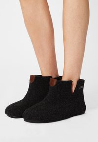 Black felt ankle boots with a rounded toe, designed with brown leather accents at the top and a flexible sole for comfort.