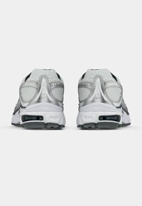 Dos zapatillas deportivas en gris y blanco con una parte superior de malla texturizada, detalles en negro y amortiguación visible de aire en la suela.