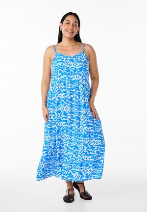 Robe maxi à motifs bleus avec fines bretelles, taille froncée et jupe fluide. Présente un design abstrait vif dans diverses nuances de bleu.