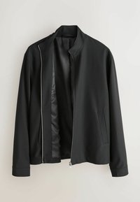 Črno jakno z ovratnikom, ki stoji pokonci, sprednjo zadrgo in enim stranskim žepom. Izdelana iz gladkega, lahko tkanine z minimalističnim dizajnom.