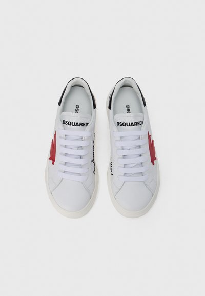 Baskets blanches avec motif de feuille d'érable rouge, accents noirs et logo sur la languette. Matière en cuir lisse et semelle en caoutchouc plate.