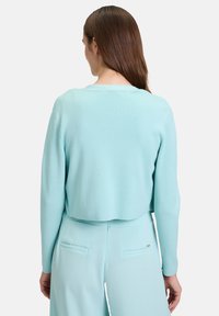 Muntgroene cropped trui met lange mouwen en een ronde halslijn, gemaakt van zachte stof; gecombineerd met bijpassende broeken met achterzakken.