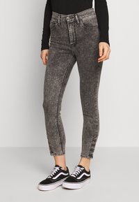 Höga svarta denimjeans med en blekt textur, med dragkedja och knappstängning samt sydda sidodetaljer. Matchas med svarta sneakers.