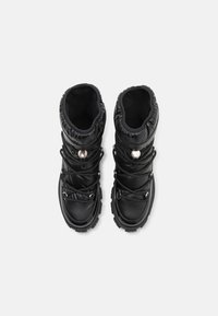 Bottes isolantes noires avec tige rembourrée, bout arrondi et semelles en caoutchouc. Dotées d'un système de laçage et d'accents métalliques pour un maintien sûr.