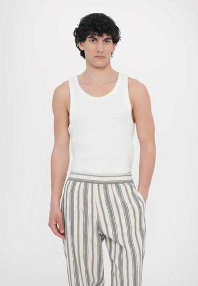 White sleeveless tank top paired with beige and gray striped pants; soft fabric, relaxed fit, elastic waistband, side pockets.