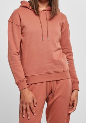 Sudadera con capucha en color rosa polvo, que cuenta con un bolsillo canguro, capucha con cordón y puños y dobladillo de canalé. Tejido de textura suave.