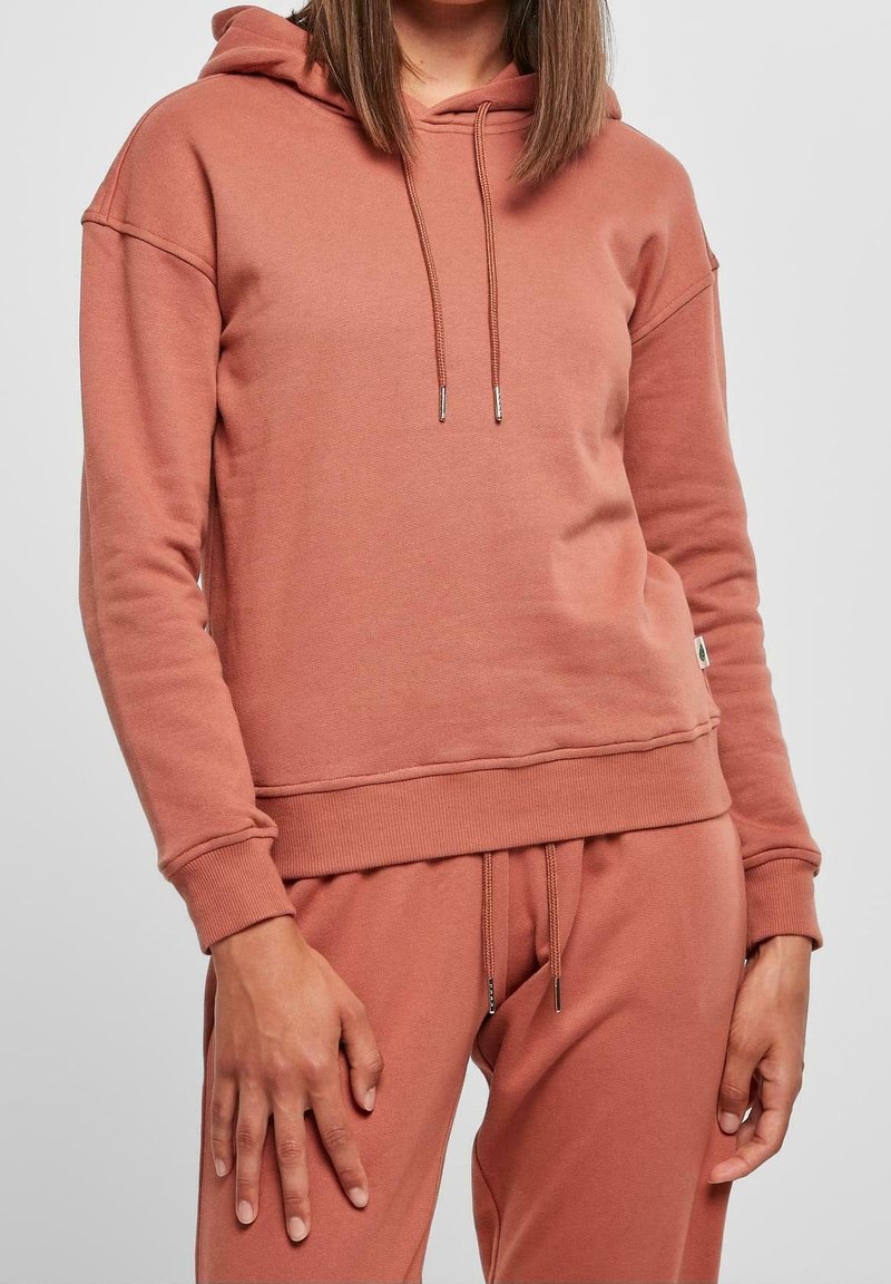 Sudadera con capucha en color rosa polvo, que cuenta con un bolsillo canguro, capucha con cordón y puños y dobladillo de canalé. Tejido de textura suave.