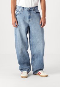 Jean en denim bleu clair avec une coupe décontractée et ample, légèrement délavé. Dispose de cinq poches, de coutures robustes et d'une fermeture à bouton en métal.