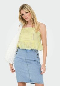 Yellow gingham crop top with a ruffled hem and cutout lace details, paired with a fitted denim skirt featuring button accents on the side.
