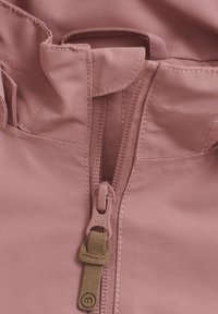 Dammig rosa jacka i tyg med upphöjd krage, med en central dragkedja i matchande färg och en brunt läderaccent på dragkedjan.