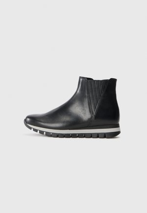 Black leather ankle boots with elastic side panels, smooth texture, rounded toe, and a contrasting white stripe on the rubber sole.