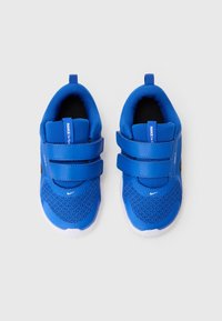 Baskets bleues pour enfants en tissu en maille, avec deux straps Velcro ajustables et des semelles en caoutchouc blanches. Logo Nike sur le côté.