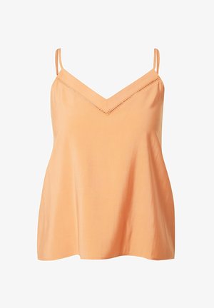 Femme portant un pantalon large pêche et un haut à fines bretelles assorti, accompagné de sandales blanches à talons hauts et lanières.