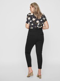 Black tapered pants with a smooth texture, paired with a floral patterned blouse featuring vertical stripes, worn with beige heels.