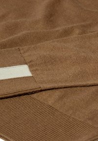 Brūns teksturēts adījuma audums ar gludu apdari, ar ribotu apkakli un izteiktu balto svītru akcents. Mīksts un elastīgs materiāls.