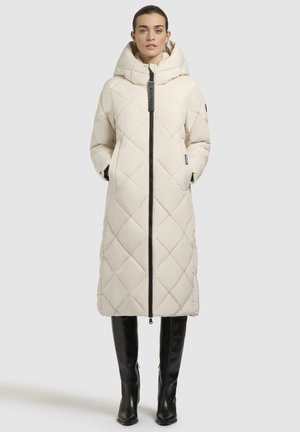 Lungo cappotto imbottito cremoso con cappuccio, zip frontale e tasche laterali. Presenta accenti neri e un motivo a diamante sul tessuto.