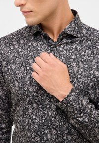Schwarzes Hemd mit floralen Mustern und Button-Down-Kragen. Verfügt über zarte weiße und graue Blumenmuster auf einem strukturierten Stoff.