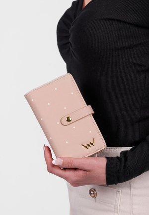 Pink faux leather wallet with white polka dots, gold hardware, and a snap closure. Features a decorative logo at the bottom.