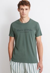Vihreä puuvillapaidan t-paita, jossa on lyhyet hihat ja pyöreä p�ääntie. Etupuolella teksti "Marc O'Polo EST. IN STOCKHOLM" tummalla fontilla.