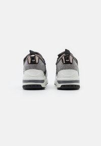Des sneakers noirs et gris présentent une tige en tissu texturé, un tirant rond, un col rembourré et une semelle intermédiaire épaisse blanche avec des accents noirs.