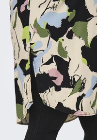 Υφασμα με λουλουδάτο σχέδιο σε κρέμα, μαύρο, μπλε, πράσινο και ροζ. Διαθέτει πλάγια σχισμή και λεία υφή, συνδυασμένο με σκούρο τζιν.