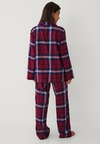 Rood en marineblauw geruit pyjama-set met lange mouwen, overhemd met kraag en bijpassende broek. Zachte stof met een ruitpatroon en een relaxte pasvorm.