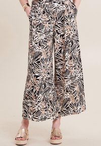 Zwart-witte wijde benen broek met een tropisch bladerenpatroon, accentueert in roségoud. De stof heeft een gladde textuur en beschikt over zijzakken.