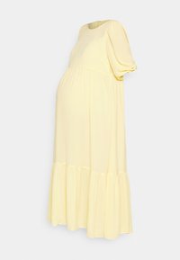 Vestido de maternidade em tecido amarelo suave, com decote arredondado, mangas curtas bufantes e uma bainha fluida com um volante na parte inferior.