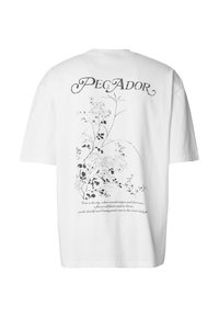 Valkoinen puuvillainen t-paita, jossa on musta kukkakuviollinen graafinen kuvio selässä ja kuvan yläpuolella sana "PEGADOR".