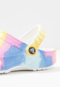 Farverig tie-dye klipklap i blå, pink og gul; lavet af holdbart materiale med en robust hvid sål og en rund logoaccent på stropperne.