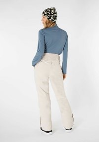 Maglietta a maniche lunghe blu chiaro abbinata a pantaloni color crema, con un cinturino testurizzato e un berretto a motivo bianco e nero.