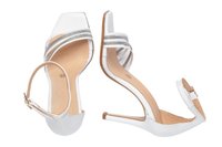 Sandalias de tacón alto blancas con punta cuadrada, correas metálicas plateadas y un tacón delgado. Parte superior de cuero suave y plantilla beige.